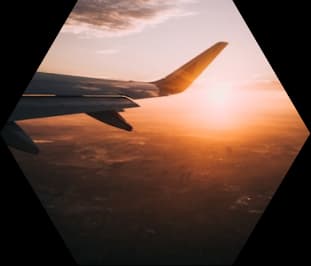 An aeroplane wing above the clouds at sunset